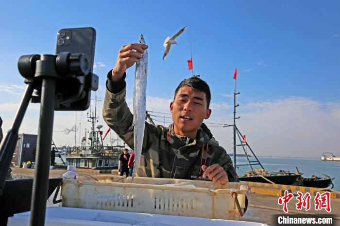 图为变身为“网红”的渔民们，手握新鲜的海鲜，向天南海北的粉丝们推介日照特色海鲜。　薄林 摄